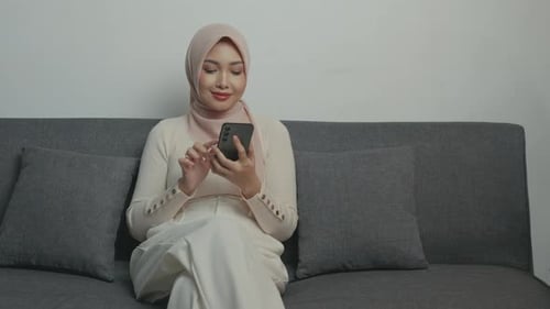 Smiling Woman on Sofa Using Phone