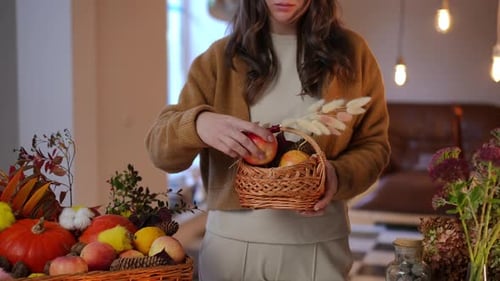 Woman Arranges Autumnal Fruit in Small Basket