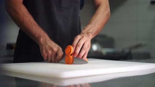 Hands Slicing Carrot with Knife on Cutting Board