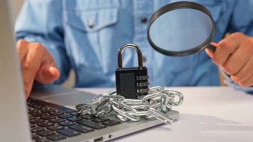 A person examines a padlock wrapped in heavy chains.