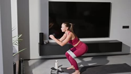 Woman Doing Squats with Resistance Band at Home