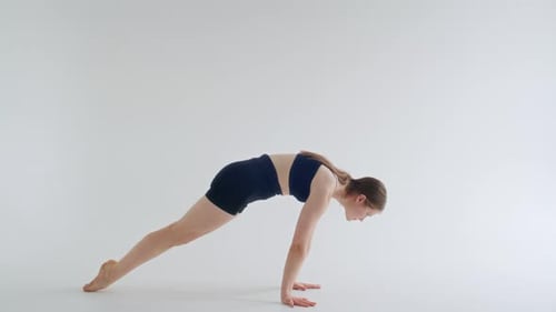 Jeune femme pratiquant la pose de Bakasana dans un studio de yoga minimaliste