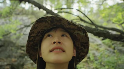 Asian Female Hiker Looking at Trees in Forest