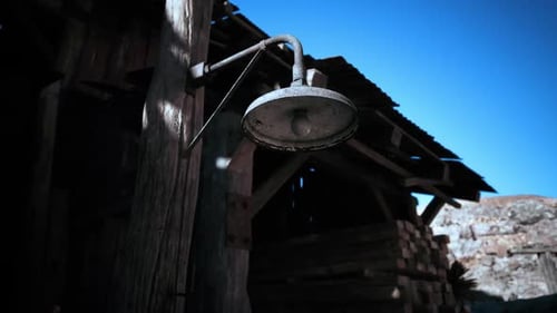 Old Metal Lamp Hanging Outside a Rustic Wooden Shed Under a Clear Blue Sky