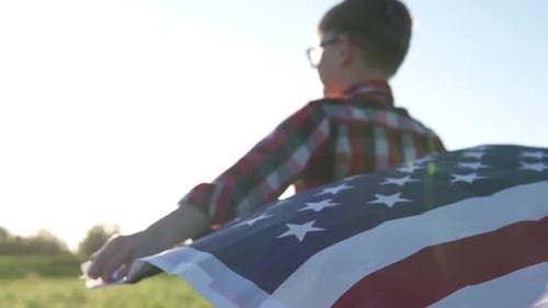 Boy Holding American Flag in Grassy Field