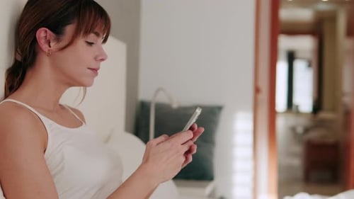 Woman Using Phone While Sitting in Bed