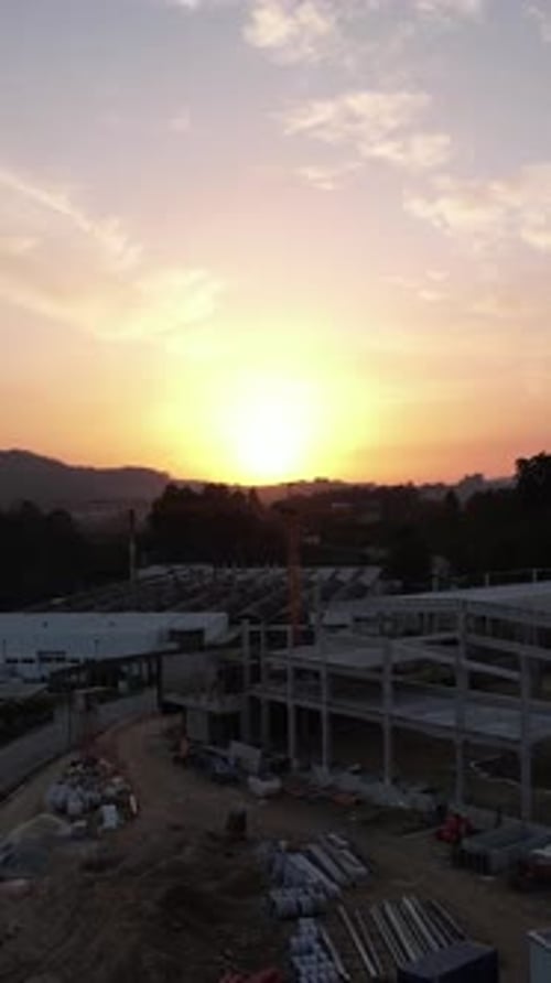 Vídeo vertical de una grúa en la construcción de edificios al atardecer