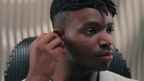 Young Adult Man Inserts Wireless Earbud