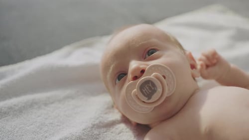 Nettes nacktes Kleinkind saugt Schnuller