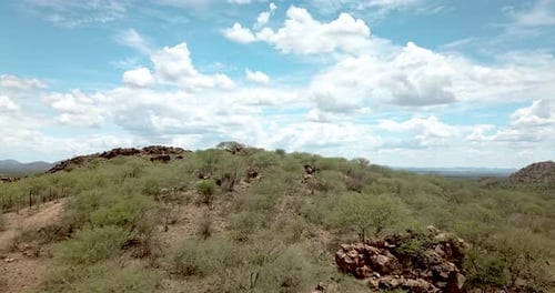 Forward moving drone shot over a mountain on a dry game farm near Okahandja, Namibia, showing the va