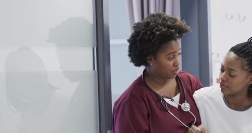 Afroamerikanische Ärztin hilft Patientin beim Gehen im Krankenhauskorridor, Zeitlupe