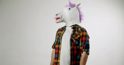 Mann in Einhornmaske zeigt etwas auf weißem Hintergrund