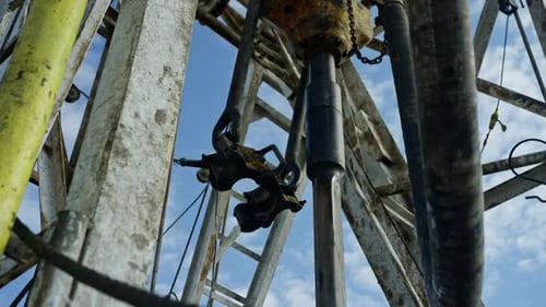 Metal bar rotating in the drilling equipment. Tower for oil and gas production. Low angle view.