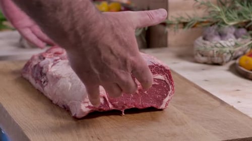Close up of a professional butcher's hands placing a large, prime marbled raw beef roast onto a