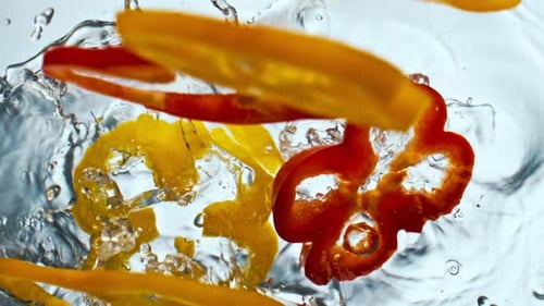 Colorful Sliced Bell Peppers Falling into Water