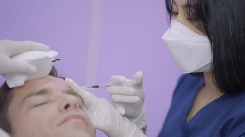 Professional Cosmetologist Making Injection of Botulinum Toxin Into Face of Young Patient