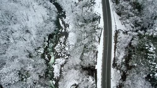 Aerial View of Snowy Forest, Mountain Road and River in Winter
