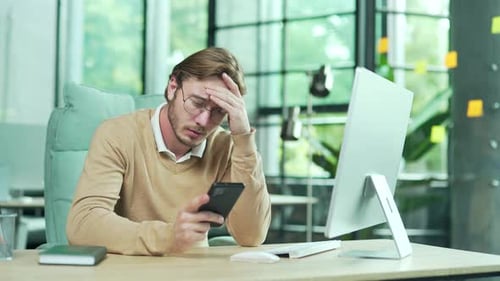Nervous frustrated young business man office worker with glasses received email message on smartphon