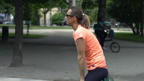 Attractive young woman resting on park bench after jogging in super slow motion