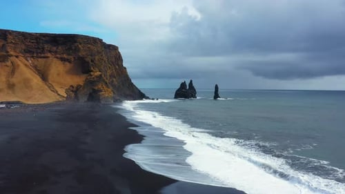 Sharp Cliffs on Black Sand Beach of Reynisfjara with Waves Hitting the Shore Vik Iceland