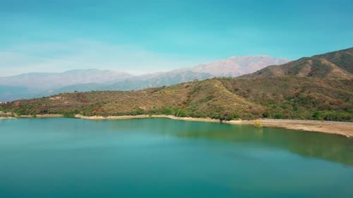 Aerial drone flying over a blue water lake with mountains landscape
