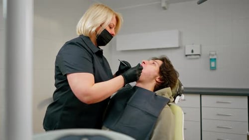 Dental Office Doctor Blonde Dentist in Black Uniform Consulting Patient Examining the Mouth