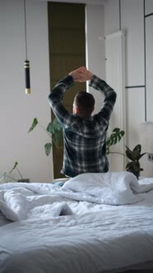 Young Man Stretches After Waking Up in Bed