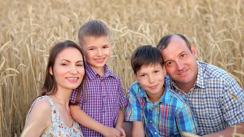 Une famille heureuse montre un sourire plein de dents sur un champ de blé mûr