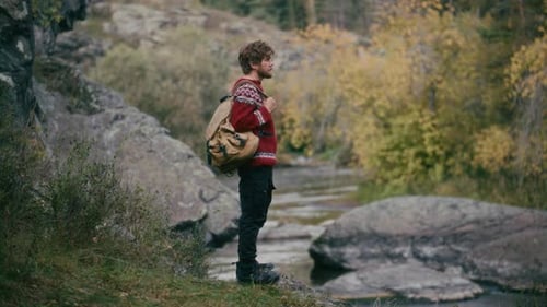 Hiker Enjoying Scenic Nature, then Walking along Riverbank in Autumn Forest
