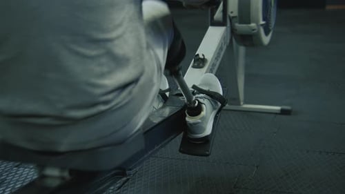 Athlete with Prosthetic Leg Exercises on Rowing Machine in Gym