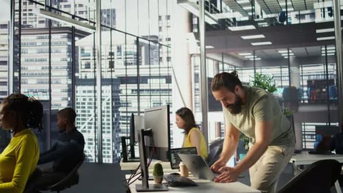 Mann überwacht Firmensysteme mit einem Notebook, während er im Büro steht
