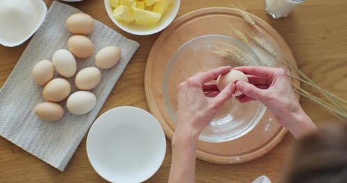 Femme cassant un œuf en farine pour faire du pain selon la recette traditionnelle