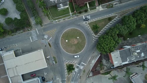 Top down aerial drone view of a small traffic roundabout on a quiet road