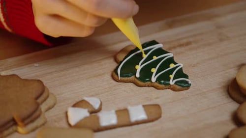 She Adds Yellow Icing to a Green Christmas Tree Cookie, Creating a Festive Look with Careful Details