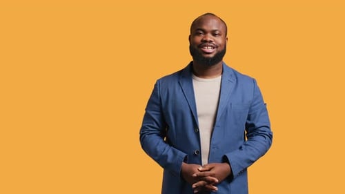 Smiling Man in Blue Suit on Orange Background