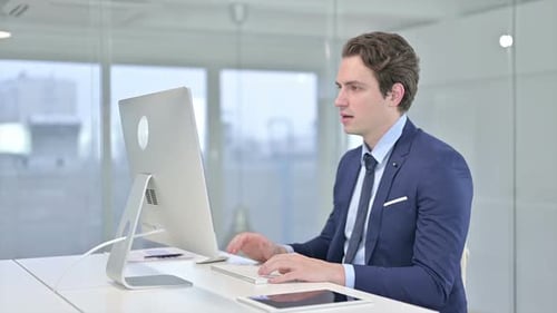 Ambitious Businessman Celebrating Success on Desktop in Office