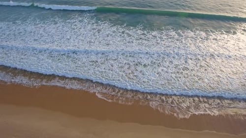A Nostalgic and Dramatic Aerial View of the Waves Crashing Onto the Beach