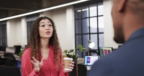 Two happy diverse creative colleagues in discussion in casual office, slow motion