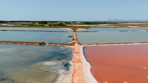 Pink Salt Evaporation Ponds Create a Striking Contrast with the Turquoise Waters Under a Clear Blue