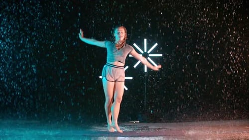 Young girl modern dancer dancing in the rain, slow motion effect