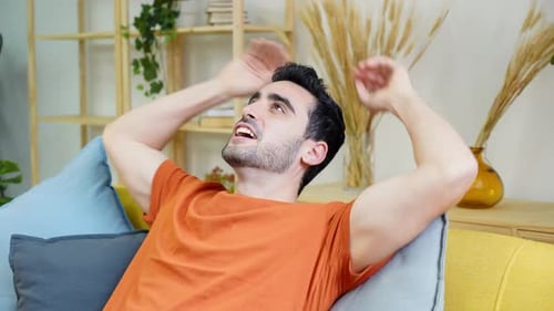 Man Reclines Smiling on Couch At Home