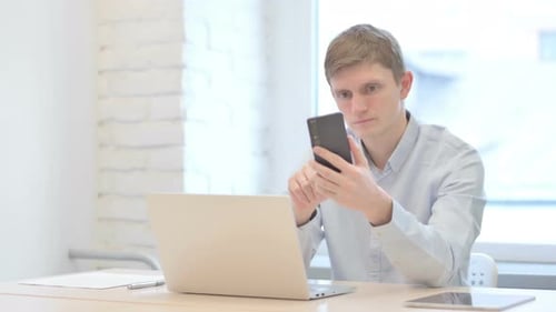 Young Adult Using Phone at Desk