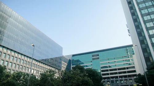 Camera is starting to record and holding steady, showing teal-green office building and trees