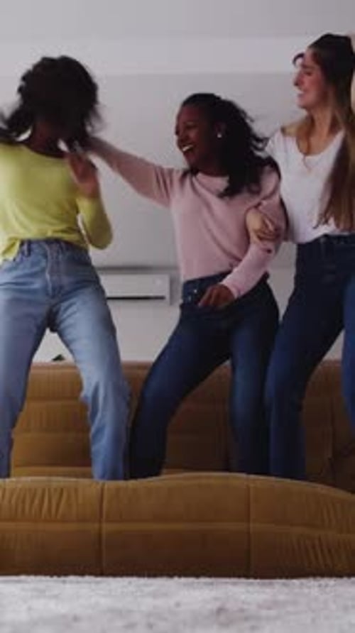 Three Friends Jumping on Couch Laughing