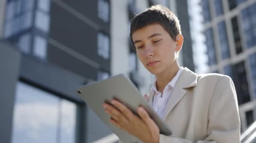Portrait of the Businesswoman Standing in Formal Brown Suit Using Digital Tablet and Answering Work