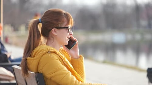 Young Woman Talking on Phone in City Park