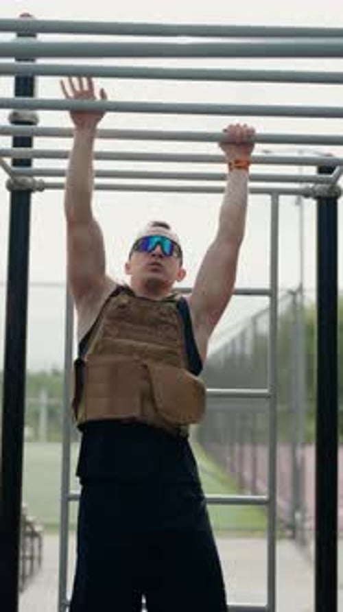 Muscular Man Training on Monkey Bars with a Weighted Vest