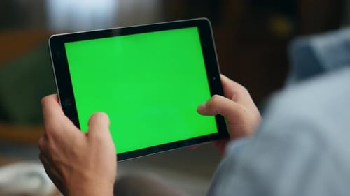 Man Using Tablet with Green Screen in Home
