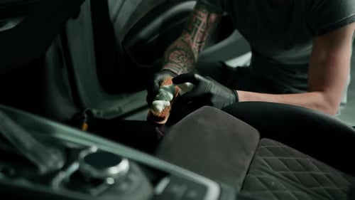 Man Cleaning Interior of Car with Brush and Foam