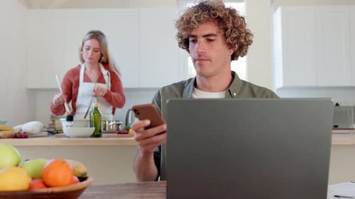 Man Works on Laptop, Takes Call in Kitchen